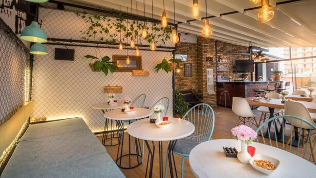 A restaurant with round tables, hanging lights, and a brick wall. - Levent Hotel Istanbul (Istanbul)