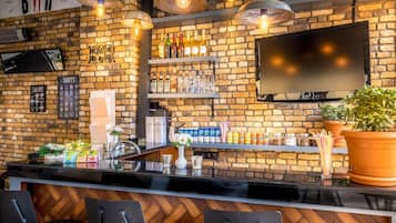 A bar with a brick wall, shelves of bottles, a TV, and a potted plant.