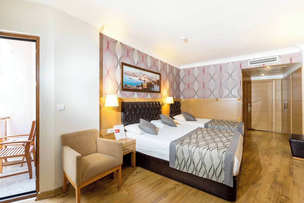 A hotel room with a bed, a chair, a desk, and a door.