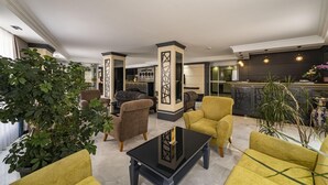 Um lobby de hotel moderno com área de estar, um bar e uma cozinha ao fundo.