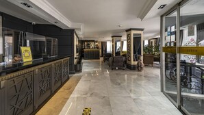 A hotel lobby with a reception desk, seating area, and a glass wall with a bicycle outside. - Levent Hotel Istanbul (Istanbul)