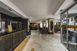 Un vestíbulo de hotel con mostrador de recepción, zona de estar y un muro de cristal con una bicicleta afuera.