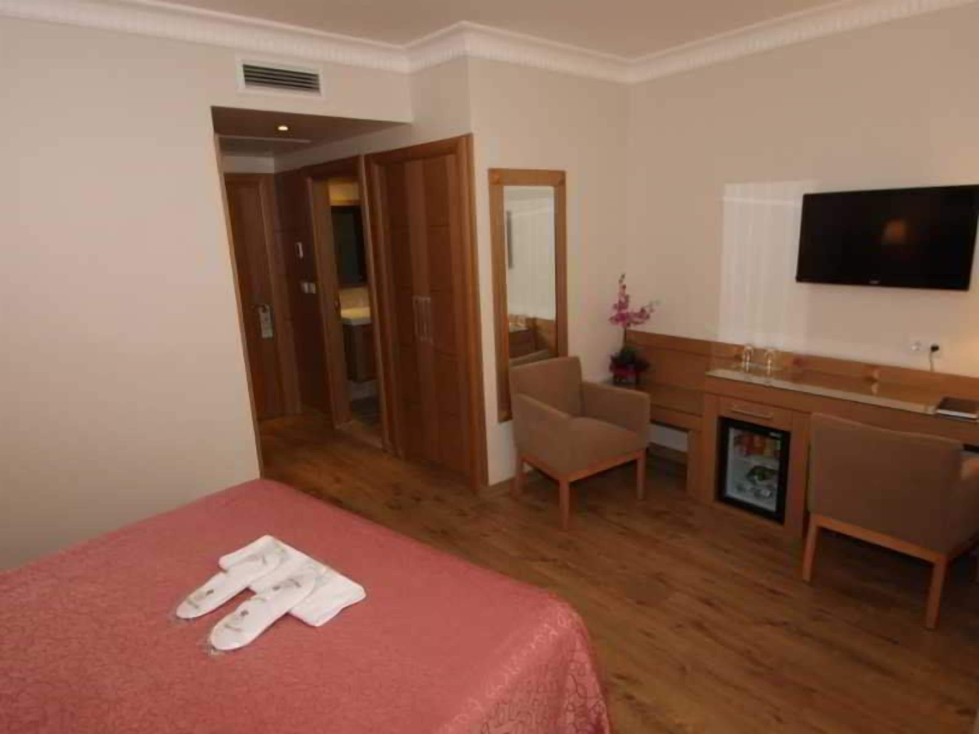 Ett hotellrum med en säng, ett skrivbord, en stol, en tv och ett badrum.