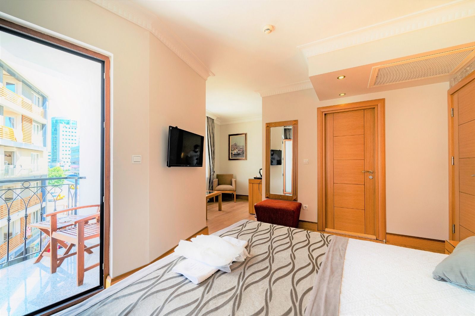 Ett hotellrum med en säng, en TV, en balkong, en stol, ett skrivbord och en garderob.