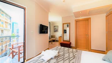A hotel room with a bed, a TV, a balcony, a chair, a desk, and a wardrobe.