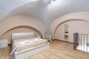 A bedroom with a bed, a chair, a nightstand, a mirror, and a balcony.