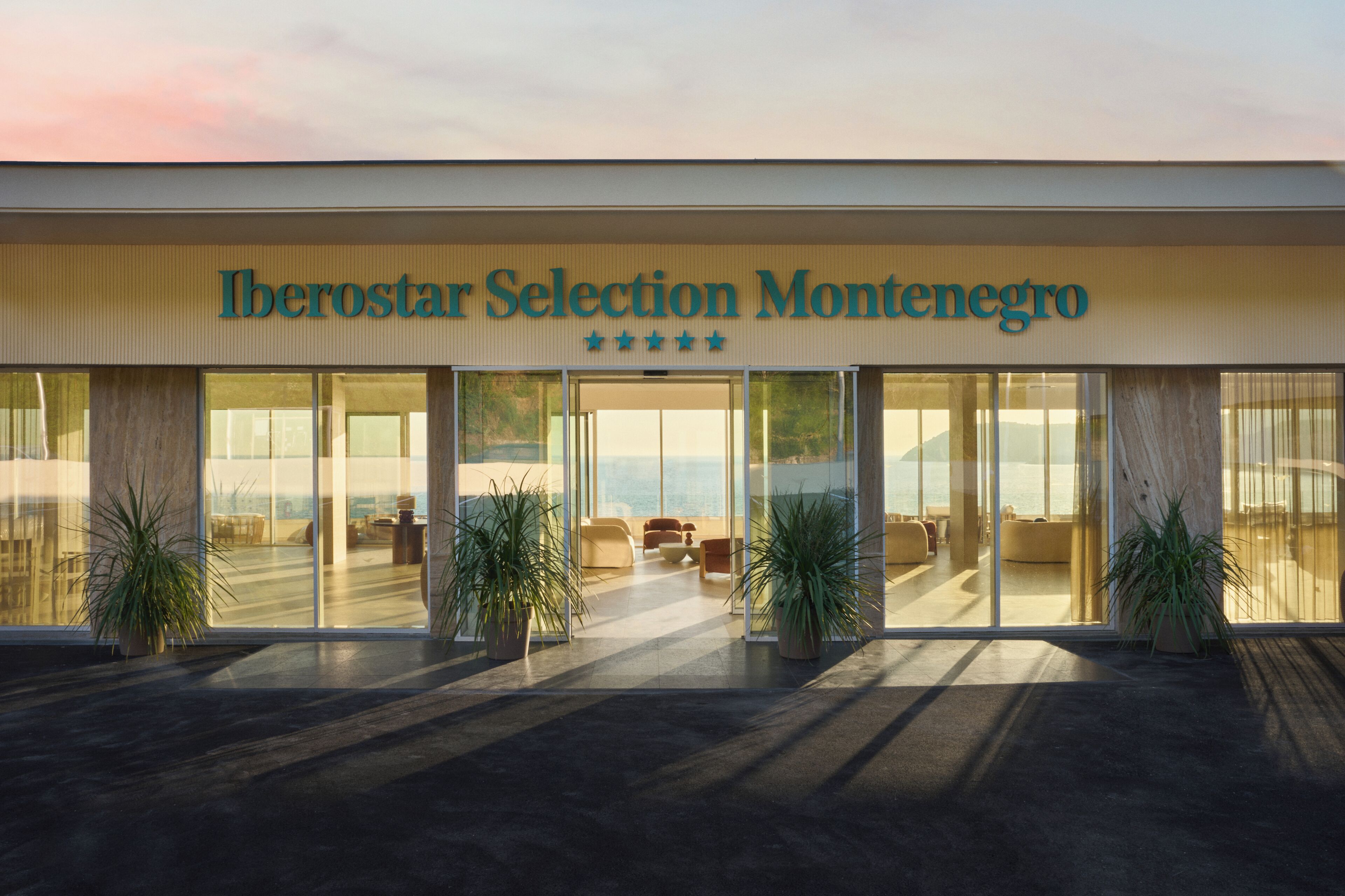 A hotel with a modern facade, large glass windows, and a view of the ocean.