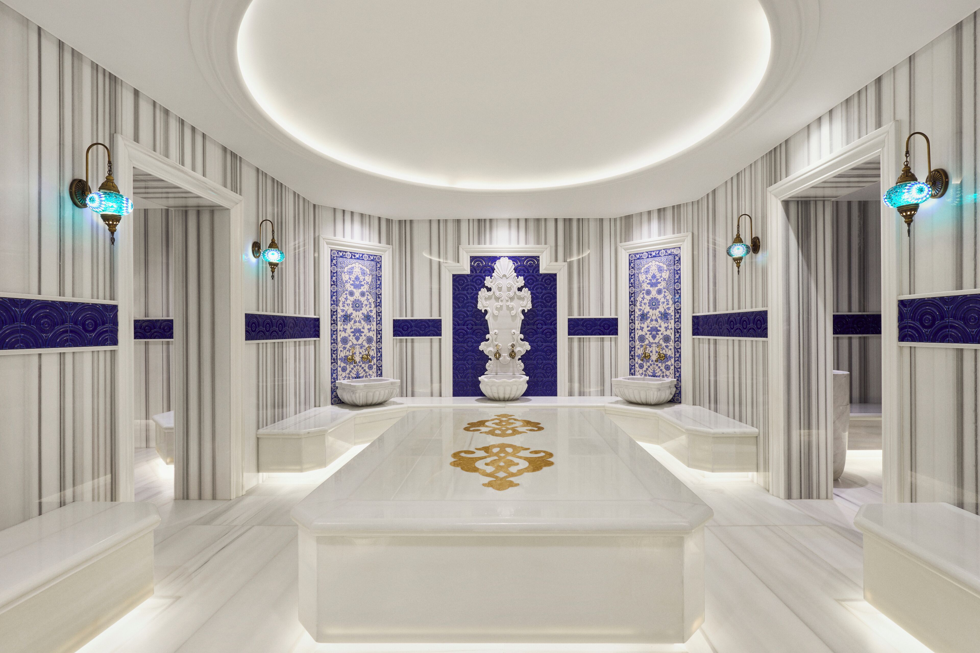 Un hall d’hôtel luxueux, avec un sol en marbre, des panneaux muraux richement décorés et des luminaires élégants.
