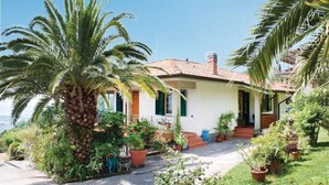 A house with a tiled roof, a porch, and potted plants.