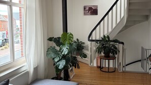 Ein modernes Wohnzimmer mit grauem Sofa, Holzböden und einer Treppe mit weißer Geländer.