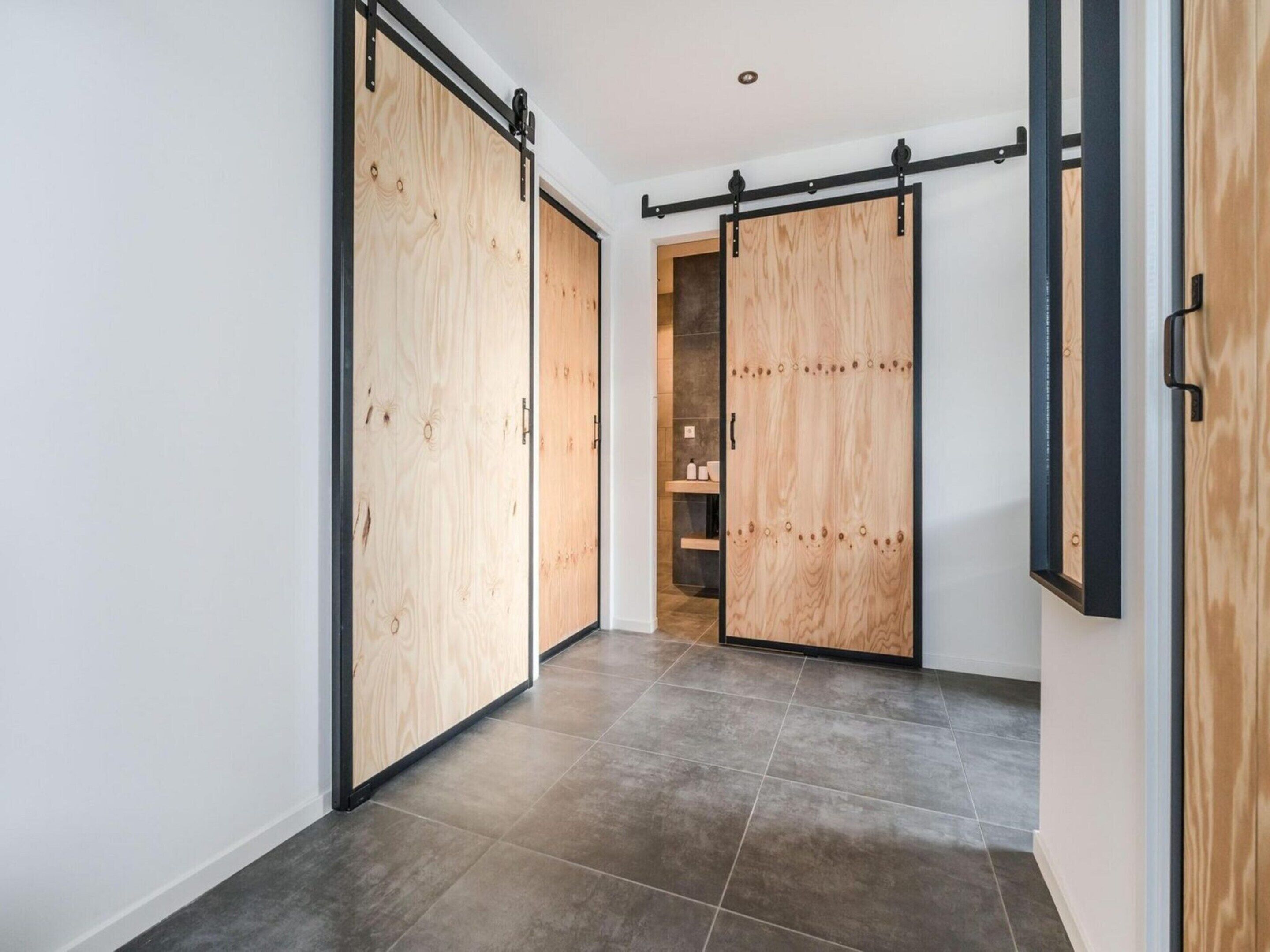 A hallway with sliding wooden doors and a tiled floor.