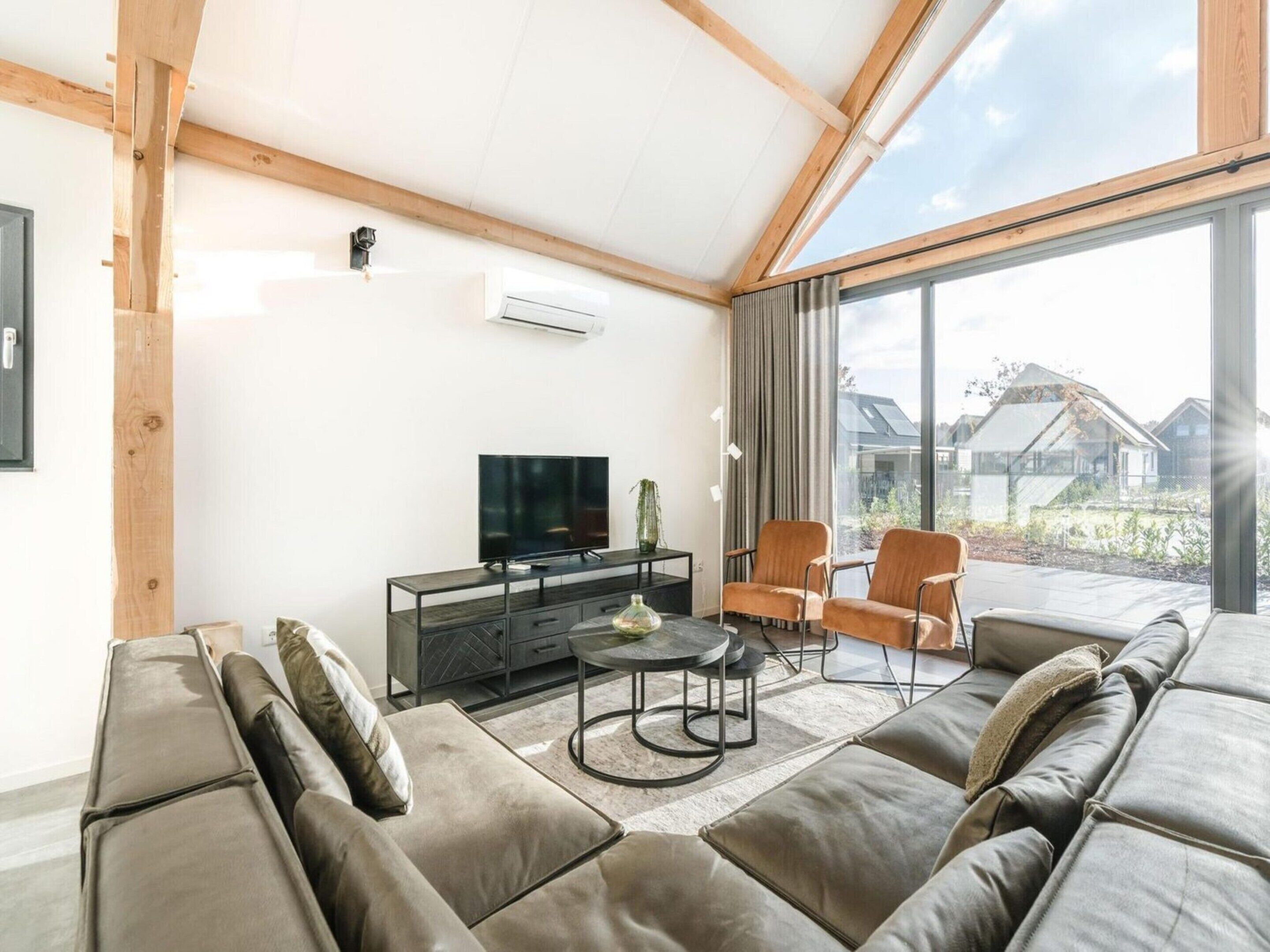 A modern living room with a sofa, chairs, a TV, and a dining table.