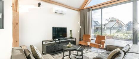 A modern living room with a sofa, chairs, a TV, and a dining table.