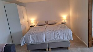 Un dormitorio con cama, mesitas de noche, armario y una silla.