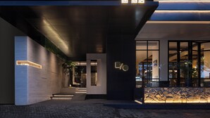 Das Hotel von außen mit modernem Design, mit einem auffälligen 'BOHOTEL'-Schild, einer Stein-Fassade und einem gut beleuchteten Eingang.