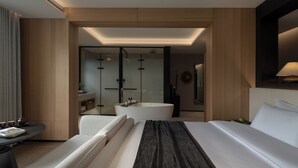 Ein modernes Hotelzimmer mit einem großen Bett, einer Sitzecke, einer Badewanne und einem separaten Badezimmer mit Duschkabine.
