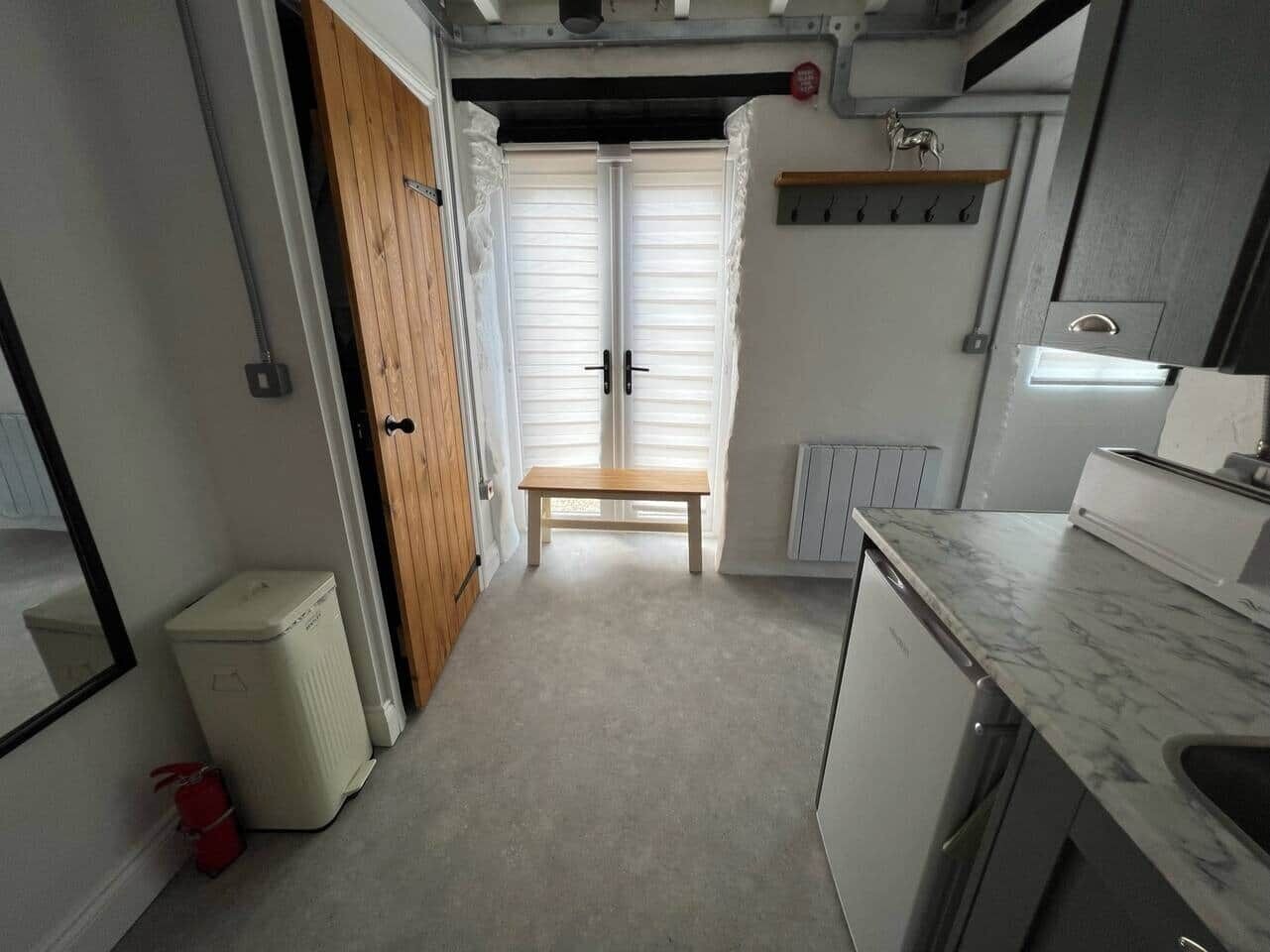 Cozinha compacta com bancada, porta de madeira e radiador.