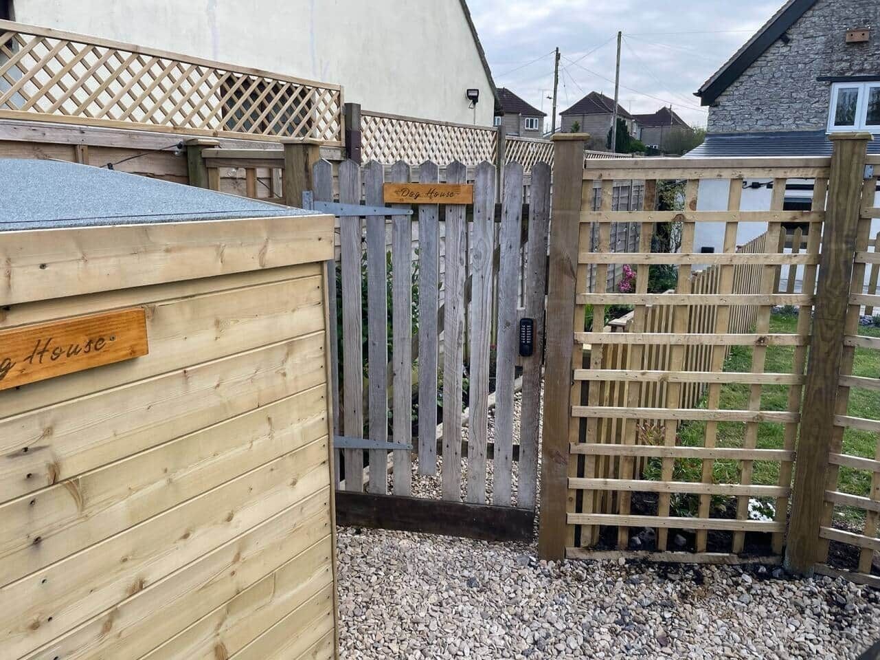 A wooden gate with a sign that reads "Dog House."