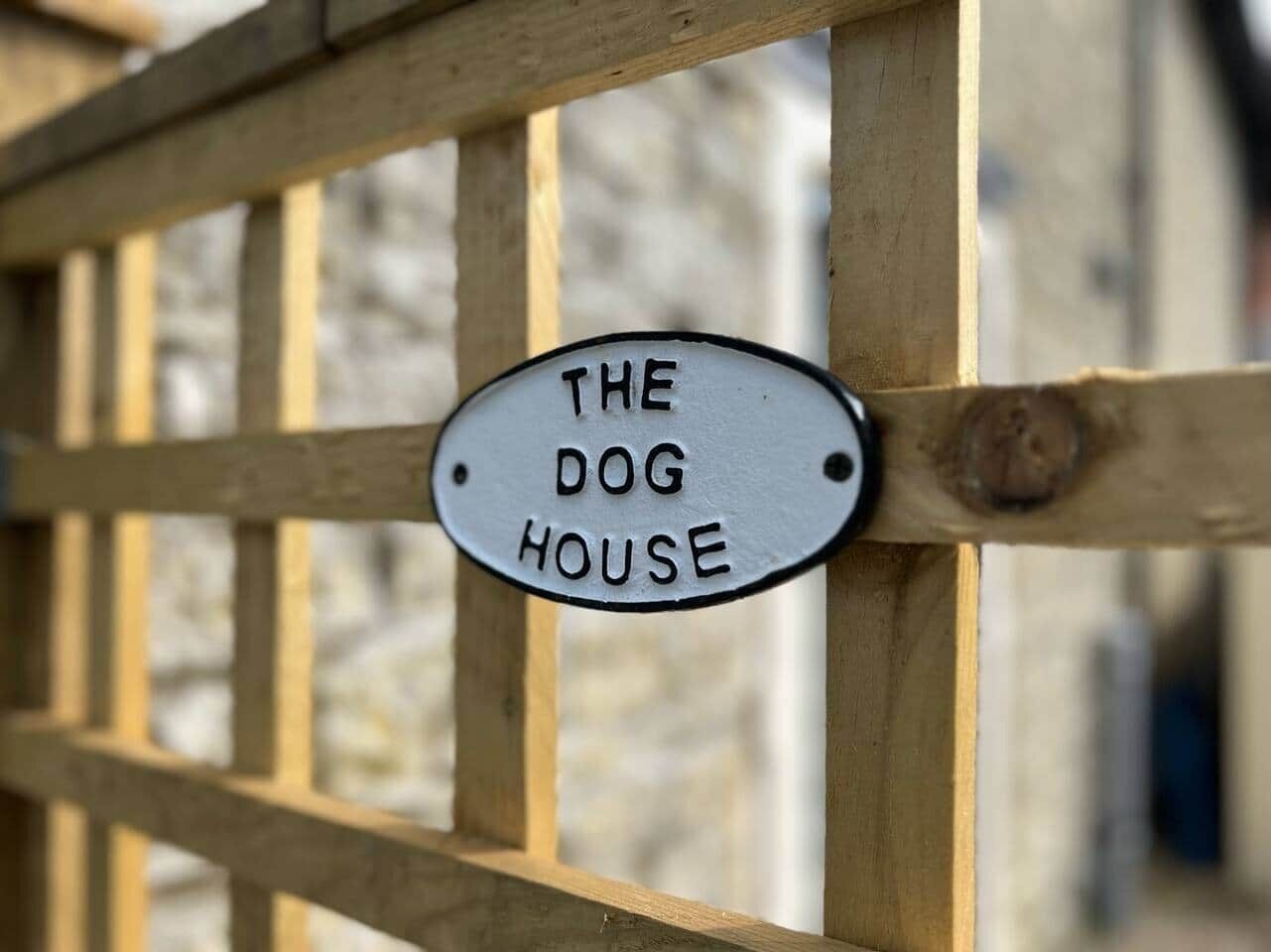 Un portón de madera con un letrero que dice "THE DOG HOUSE".