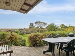 An outdoor patio with a table and chairs, surrounded by a garden with various plants and a view of the countryside. - 5 Star Holiday Home in Ebberup (Ebberup)