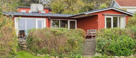 A red house with a satellite dish, a covered porch, and a stone staircase leading to the door.