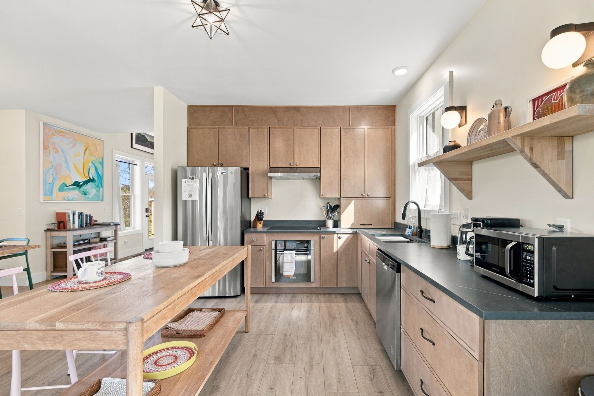 A modern kitchen with wooden cabinets, stainless steel appliances, and a dining area with a wooden table and chairs.