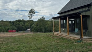 Une maison moderne dotée d’un porche abrité, de grandes fenêtres et d’une vue sur une zone boisée.