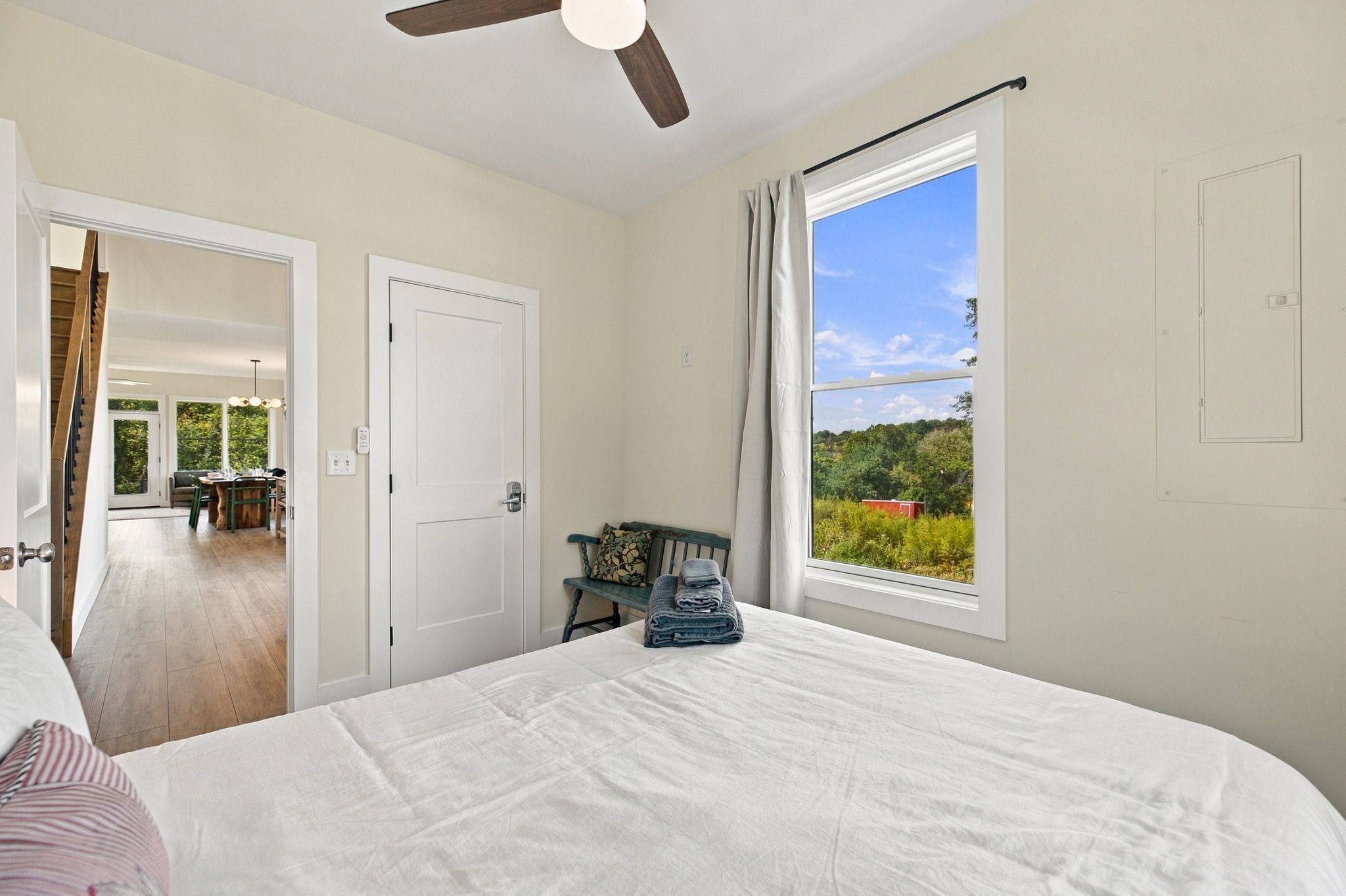 Un dormitorio con una cama grande, una ventana con vistas a la vegetación y una puerta que conduce a un comedor.