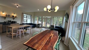 Une cuisine spacieuse avec une table à manger en bois, des chaises vertes et un luminaire suspendu au plafond.