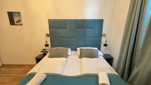 A double bed with a teal bedspread, two pillows, and two rolled towels. - Bright 1BR Apt Near Top Vienna Sights (Vienna)