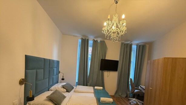A bedroom with a large bed, a TV, a desk, and a wardrobe. - Bright 1BR Apt Near Top Vienna Sights (Vienna)