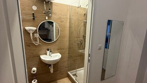 A modern bathroom with a glass shower enclosure, a sink, a mirror, and a toilet. - Bright 1BR Apt Near Top Vienna Sights (Vienna)