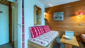 Una habitación acogedora con un banco de madera, una mesita y un calentador fijado a la pared.