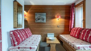 Una habitación acogedora con dos bancos de madera, una mesita y un cuadro colgado en la pared.