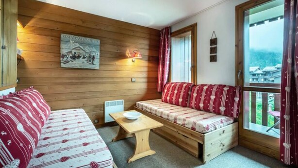 Acogedora habitación de cabaña con pared de madera, un sofá, un banco y una mesa.