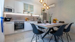 Une cuisine moderne avec un coin repas, comprenant un four à micro-ondes, un four et une table à manger avec des chaises.