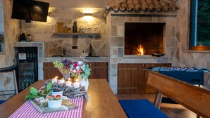Une cheminée en pierre, une table de baby-foot, un coin bar avec des bouteilles et une table où sont disposés des plats et des boissons.