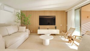 Un salon moderne avec un canapé, une table basse et un téléviseur fixé à un mur en bois.