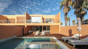Un espace piscine moderne avec une piscine à l’eau cristalline, des chaises longues et une terrasse en bois.