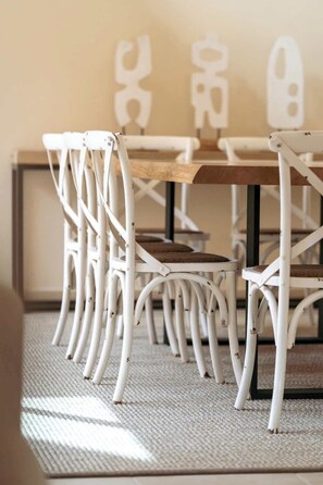 A dining area with white metal chairs and a wooden table.
