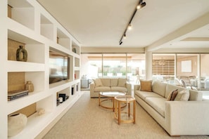 A modern living room with a sofa, coffee table, and shelves with decorative items.