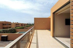 A modern building with a flat roof terrace, a glass railing, and a view of other buildings.