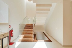 A modern staircase with glass railings and wooden steps, leading to an upper floor.