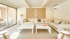 A modern living room with a sofa, two white coffee tables, and a large window. - 4BR Villa w/ Private Pool | Salgados | DA’Home (Albufeira)