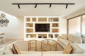A modern living room with a large TV, white shelving, and a sofa.
