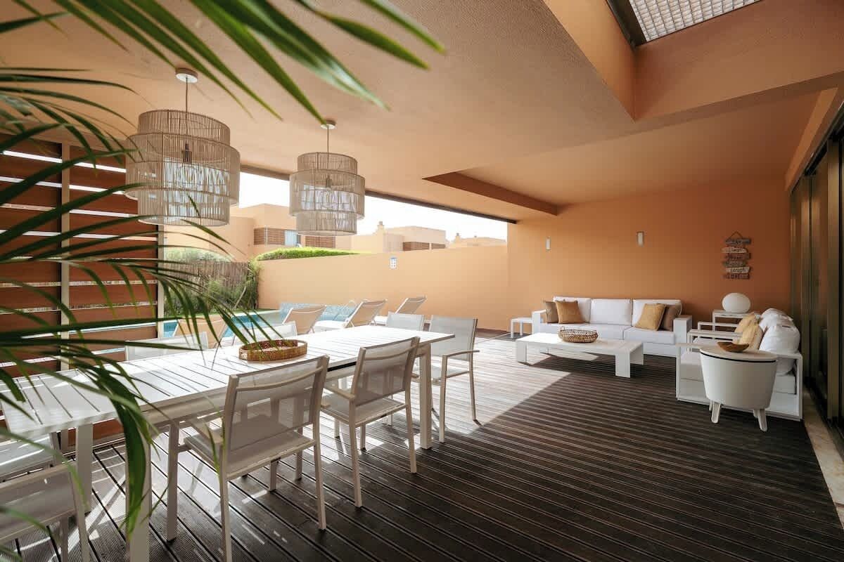 A modern outdoor living area with a dining table, chairs, and a sofa set.