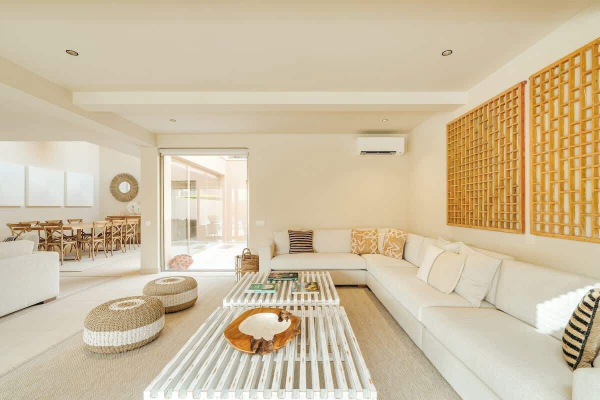 A modern living room with a white sofa, a coffee table with a wooden centerpiece, and a decorative wall panel.