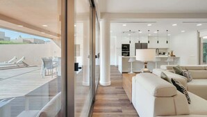 Una zona giorno moderna con un balcone, una cucina e un angolo salotto.
