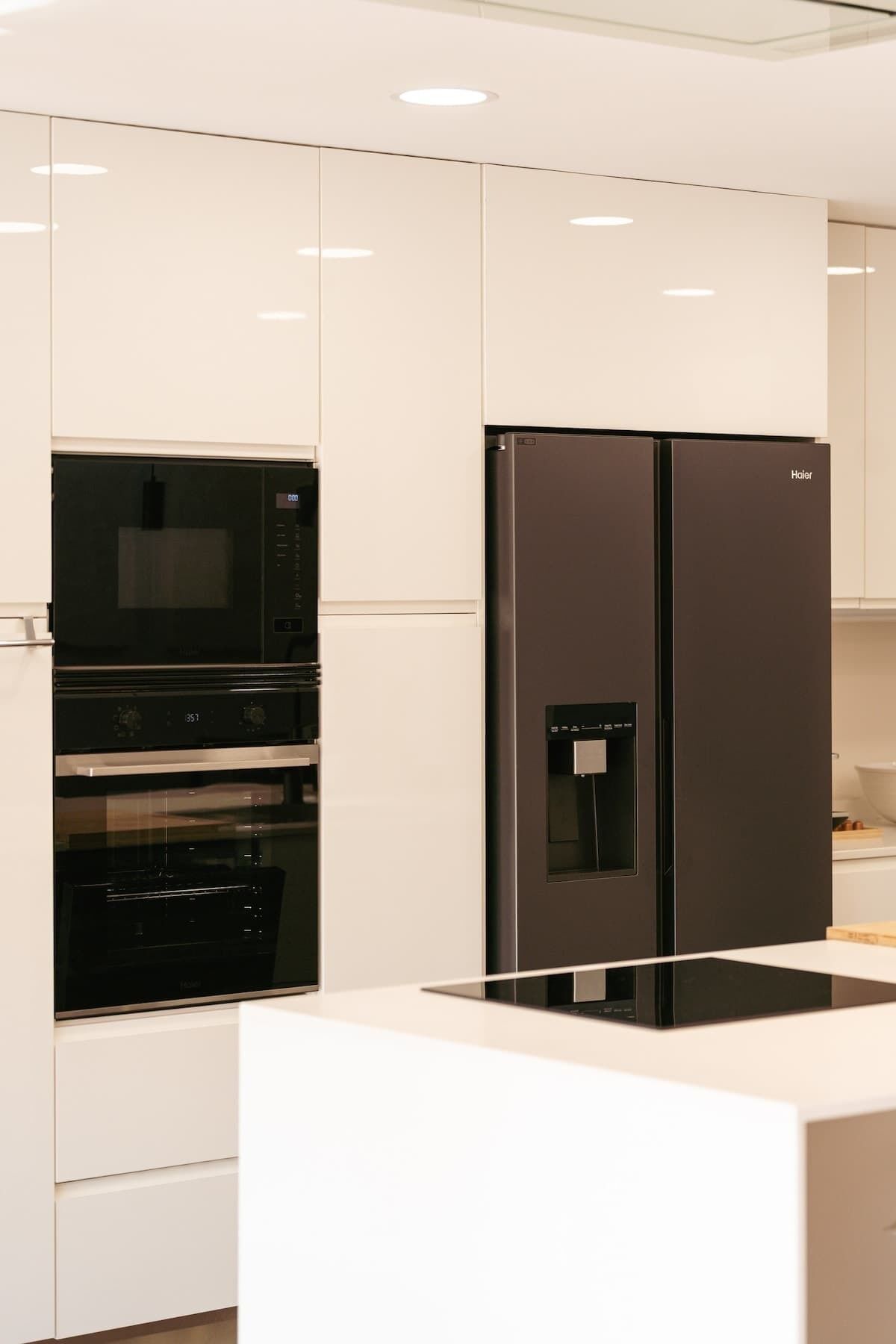 A modern kitchen with a built-in oven, microwave, and a Haier refrigerator.