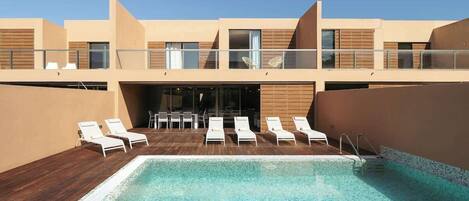 A modern pool area with lounge chairs and a clear blue pool.